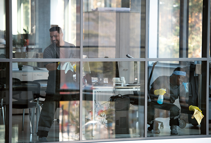 Professional cleaner sanitizing a modern commercial office during daytime